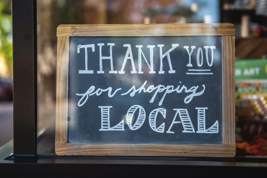a chalkboard shop local sign hangs in a boutique window