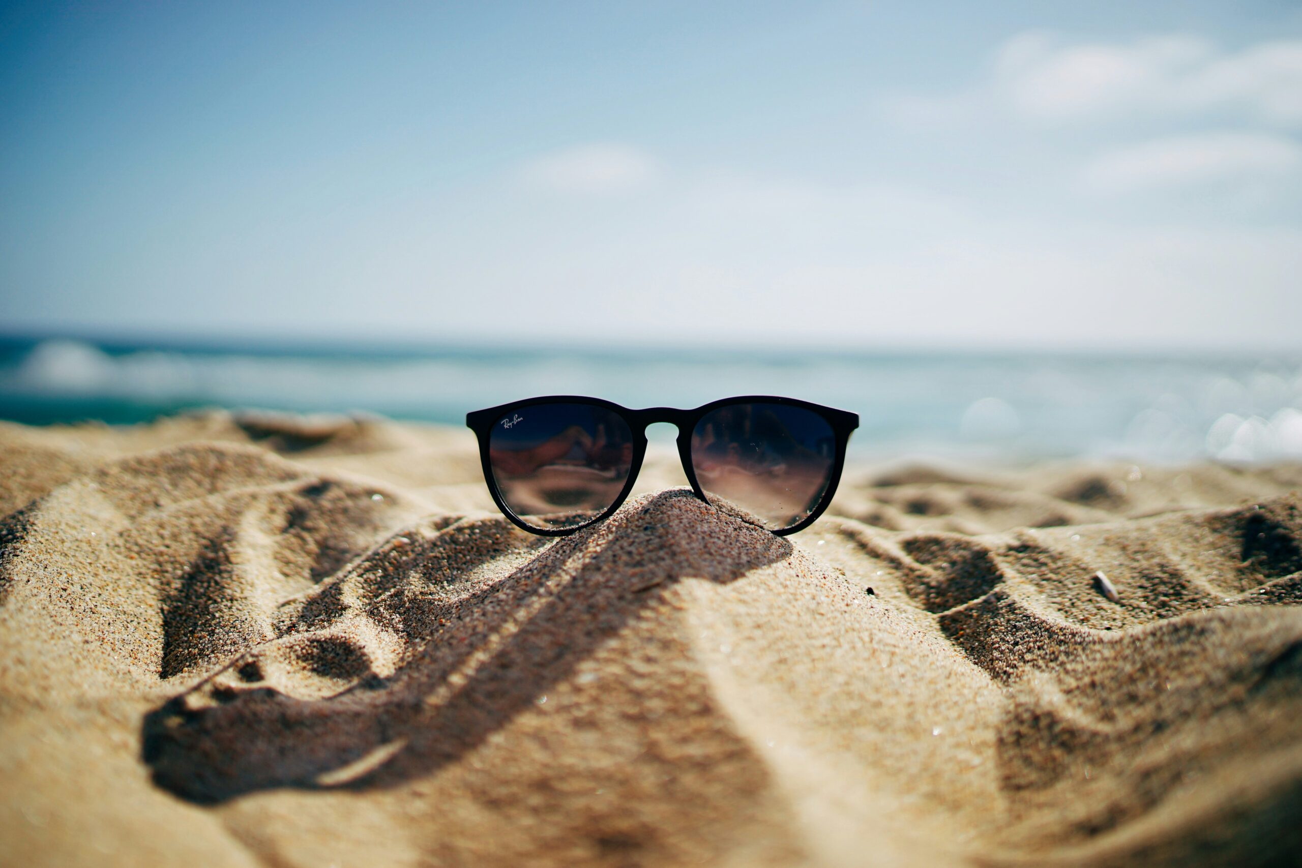 A pair of sunglasses sit on a beach