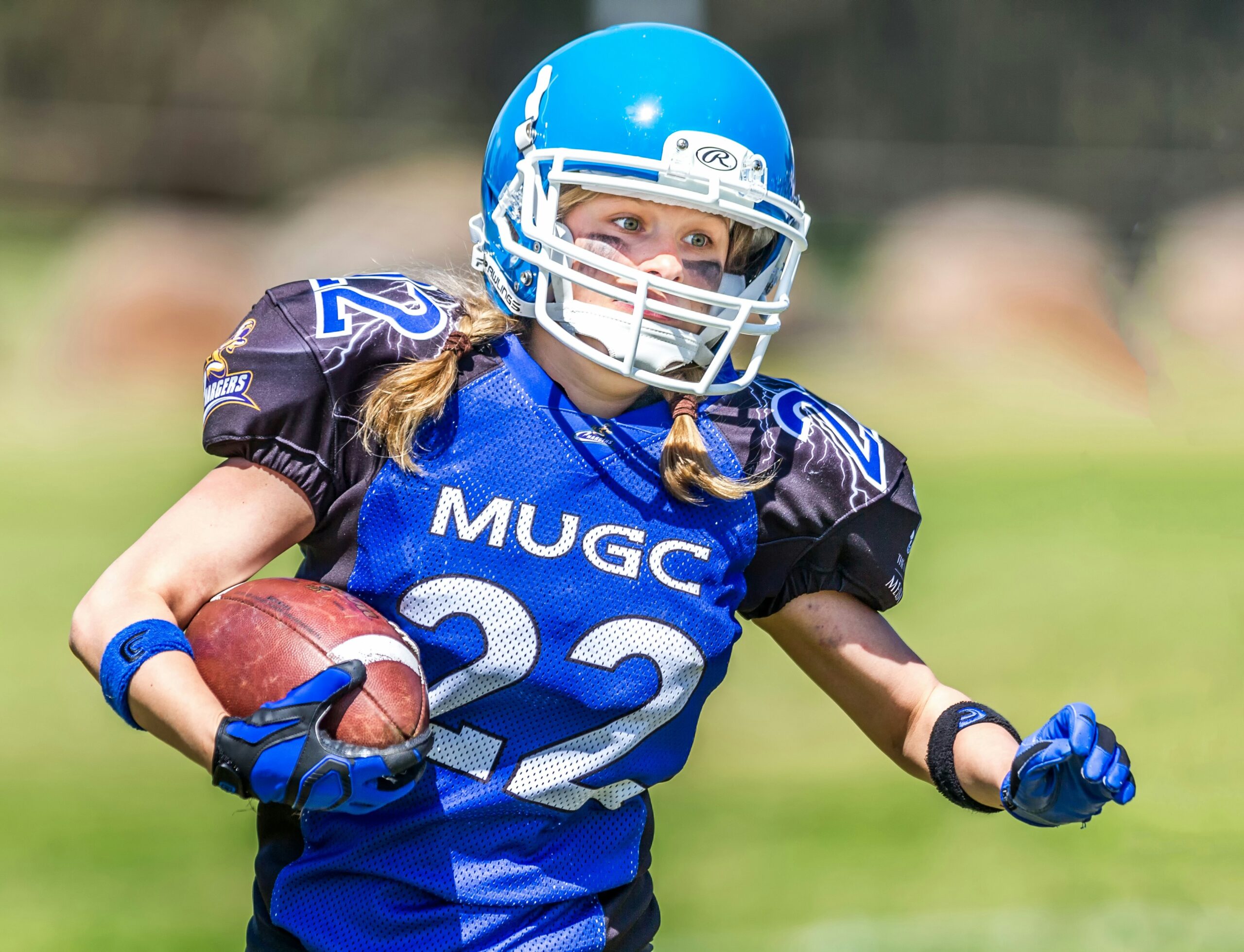 a young girl runs with a football