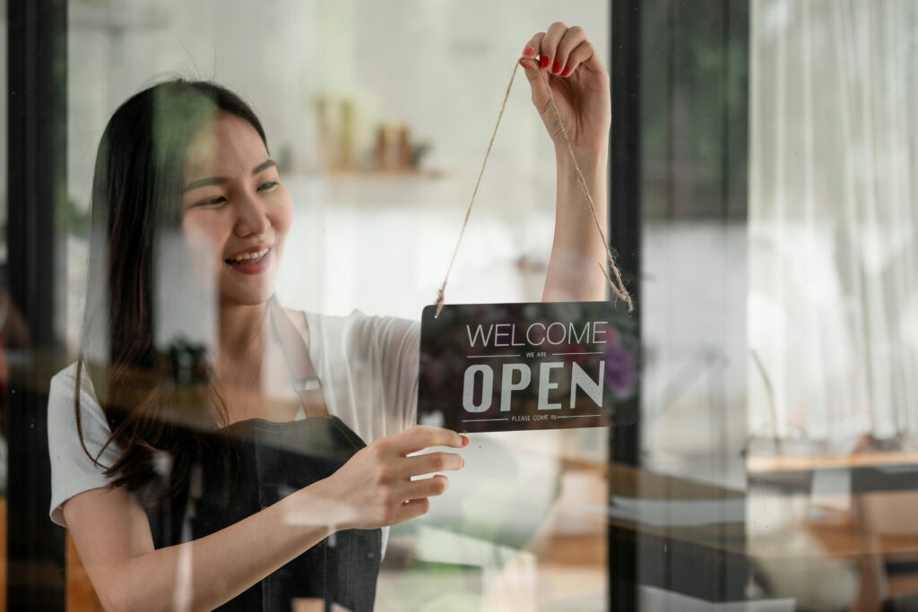 a business owner flips her open sign so customers know they can come in