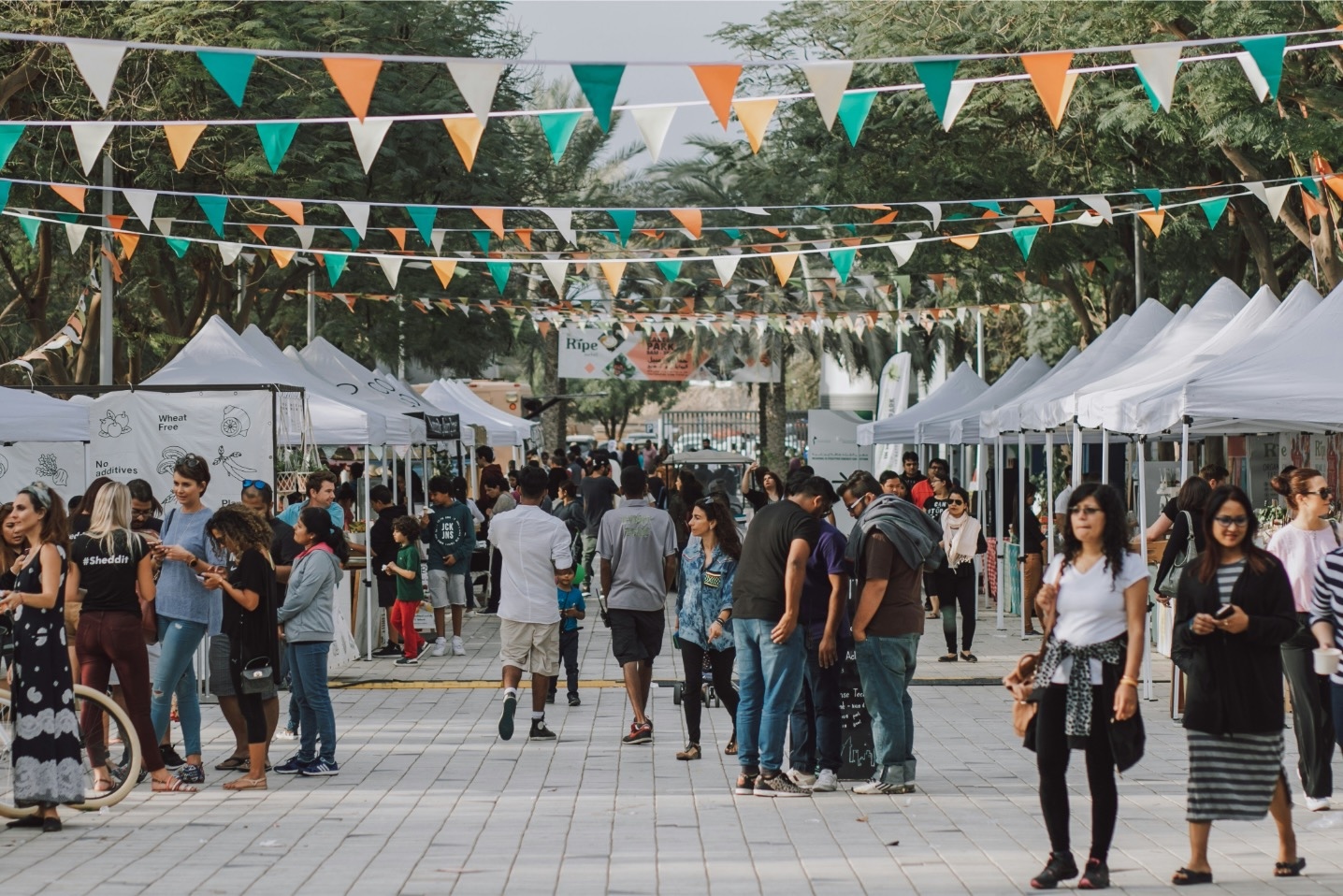 people walk around at an outdoor food and craft festival