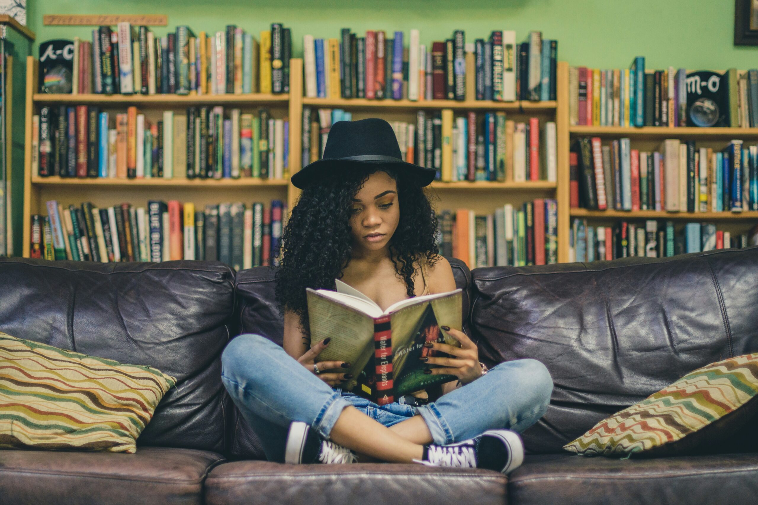 A young woman sits and reads on a comfy couch